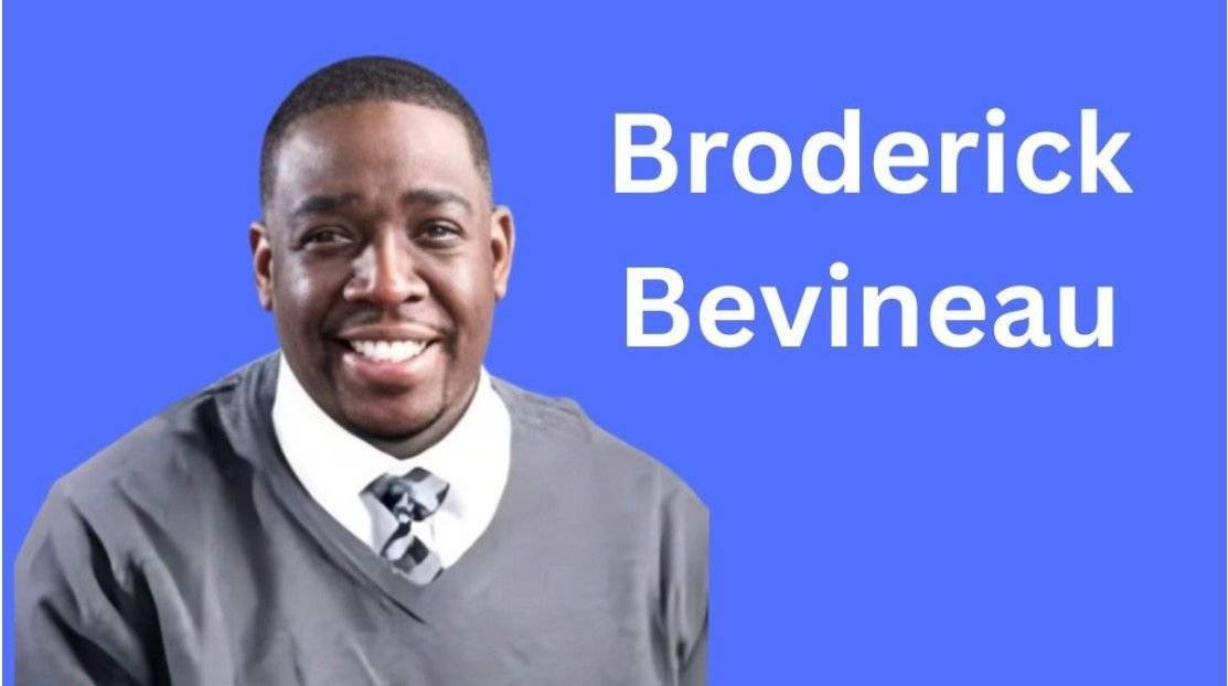 A smiling man in a gray shirt and tie, with a blue background and text showing his name.